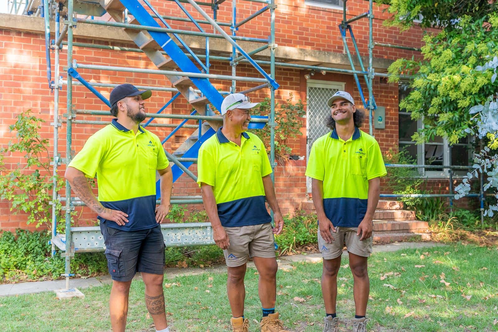 The Leaky Roof crew on site in front of a scaffolded brick house